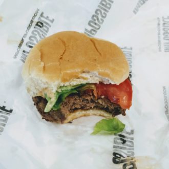 Impossible Burger in a bun with lettuce and tomato on a paper wrapper